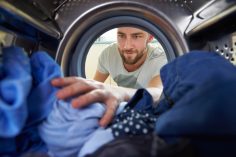 un homme devant un sèche-linge rempli de linge