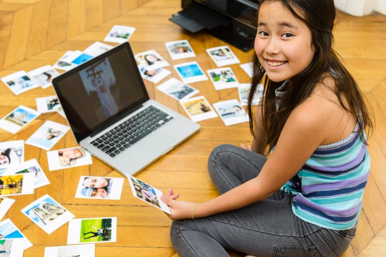 Une jeune fille regarde des photos qu'elle vient d'imprimer