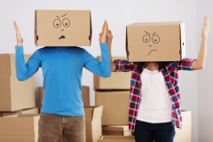 Un couple avec chacun un carton sur la tête sur lequel est dessiné un visage mécontent