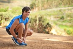 Homme accroupi qui fait les lacets de ses chaussures de running