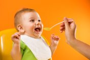 Un bébé qui sourit face à la cuillère que sa maman lui donne
