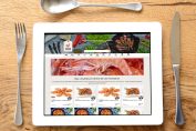 Une tablette présentée comme une assiette avec les couverts. En fond, une appli de livraison de produits frais..