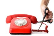 Une personne coupe le fil d'un téléphone fixe avec des ciseaux