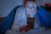 Une femme regarde dans son lit son téléphone portable dans le noir