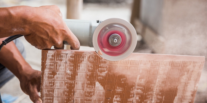 bricoleur découpant une dalle de carrelage à la meuleuse