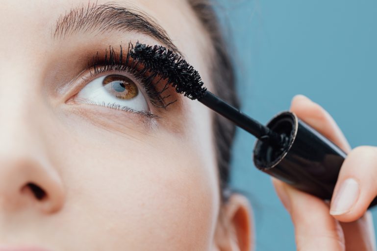 Une femme passe une brosse de mascara sur ses cils