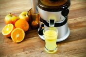 centrifugeuse, pommes, oranges et un verre de jus de fruit