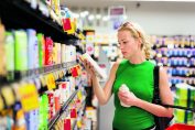 Une femme regarde un flacon dans un supermarché