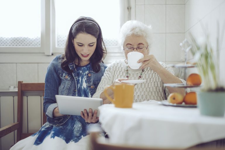 jeune femme avec une tablette aux côtés d’une femme âgée