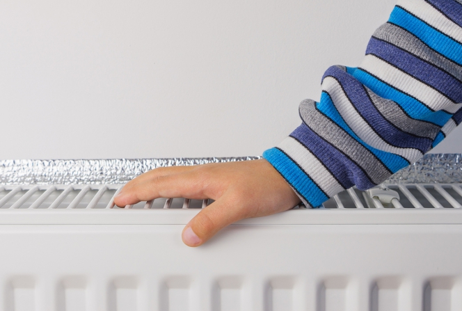 Un enfant pose sa main sur un radiateur