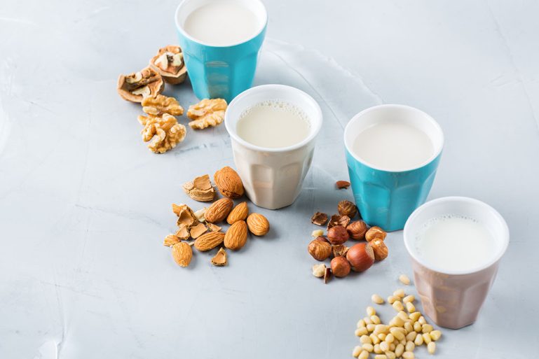 Quatre verres de laits végétaux : noix, amandes, noisettes, soja
