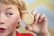 Un jeune garçon tient un biscuit à son oreille à la manière dun coquillage
