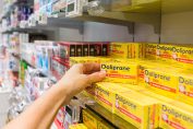 Une main prend une boîte de Doliprane 1g dans une pharmacie