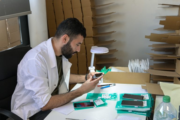 Un homme regarde un téléphone reconditionné dans un atelier