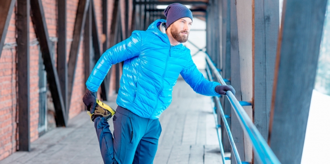 Homme en doudoune faisant du stretching