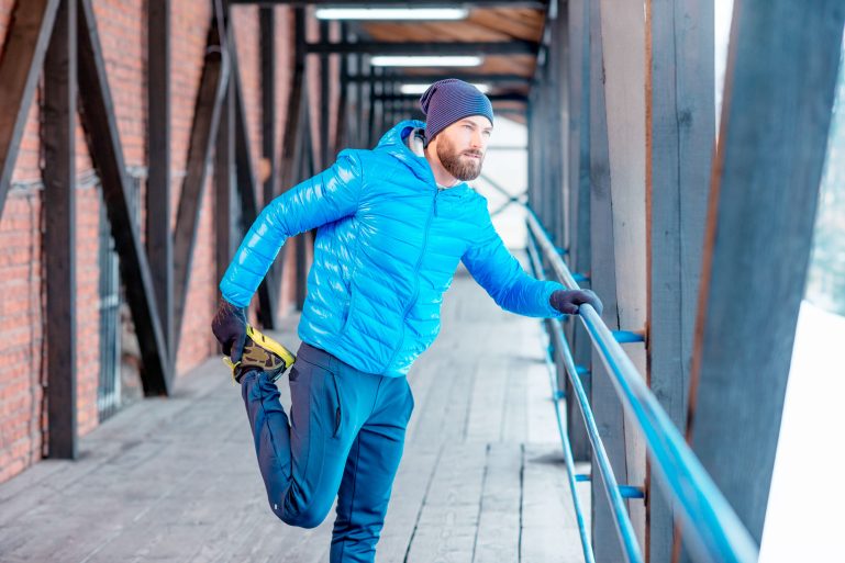 Homme en doudoune faisant du stretching