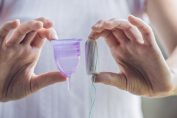 Une femme tient une coupe menstruelle et un tampon dans ses mains