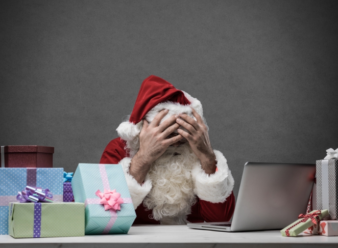 Un père Noël se tient le visage dans ses mains devant un ordinateur