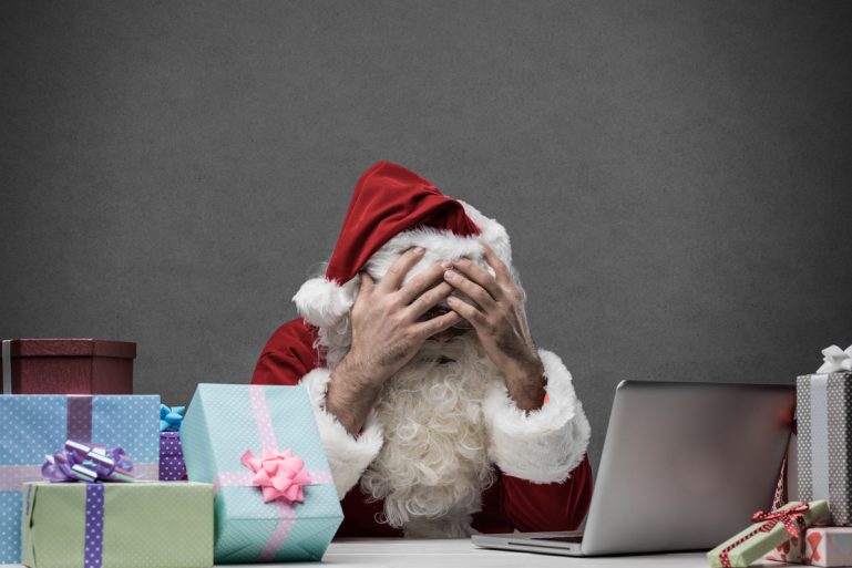 Un père Noël se tient le visage dans ses mains devant un écran d ordinateur