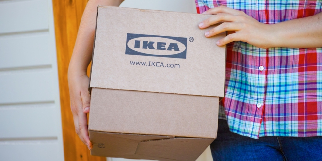 Un livreur porte un carton avec le logo Ikea