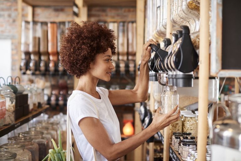 Une femme remplit en bocal en verre dans un magasin en vrac