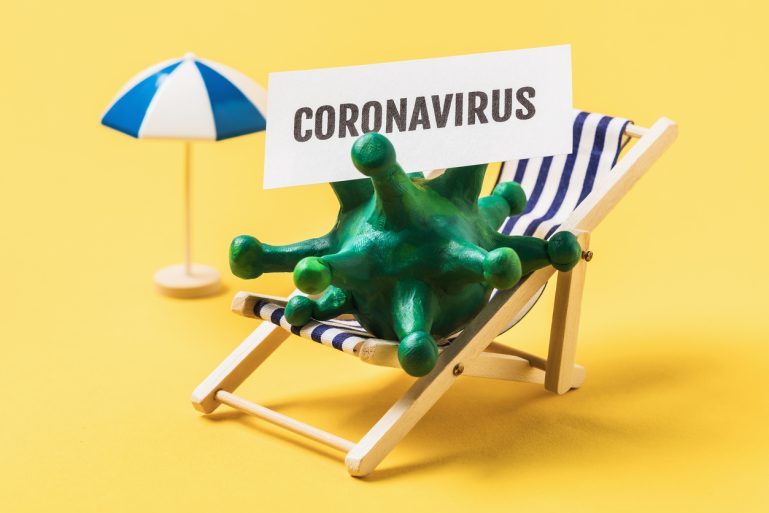 Un coronavirus assis dans un transat sur la plage