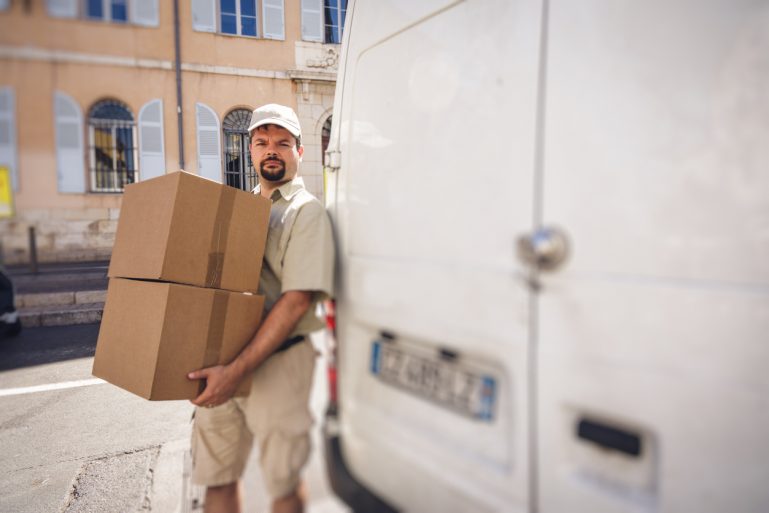 Un livreur près de sa camionnette avec deux colis
