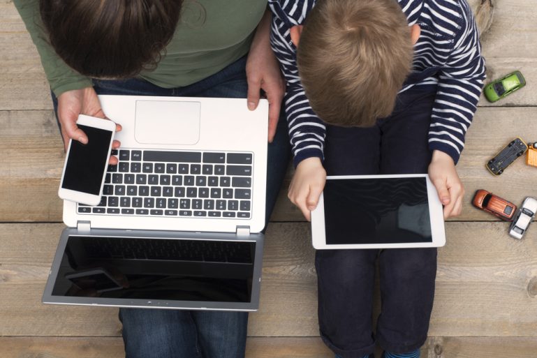 une mère avec un smartphone et un ordinateur et son enfant avec une tablette