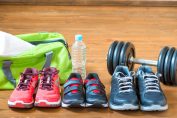 Trois paires de chaussures de sport et un haltère suer un plancher de salle de sport