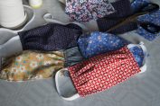 Des masques en tissus sont étalés sur une table