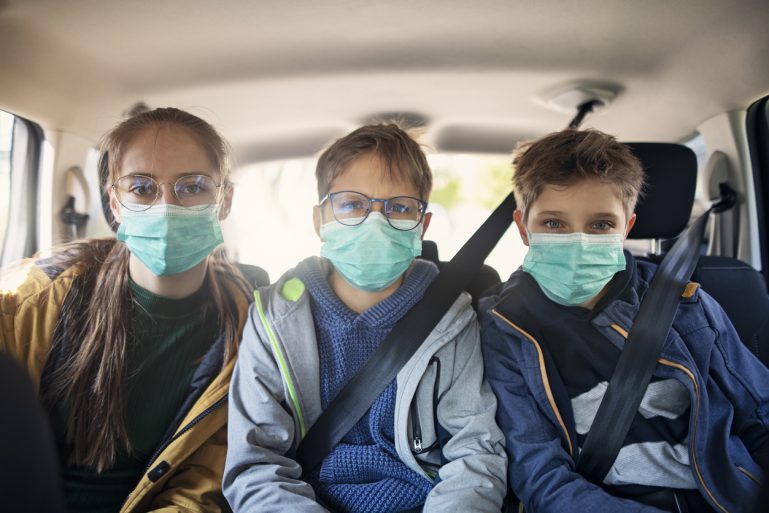 trois enfants en voiture portant un masque