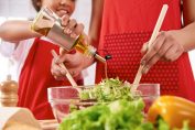 femme et fillette versant de l’huile sur une salade verte