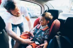 Homme attachant enfant dans siège auto