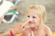 crème solaire sur le nez d'une petite fille