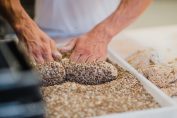 un boulanger pétrit une pâte à pain dans un bac de graines de sésame
