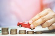 Un homme tient une petite voiture et lui fait grimper un escalier de pièces de monnaie