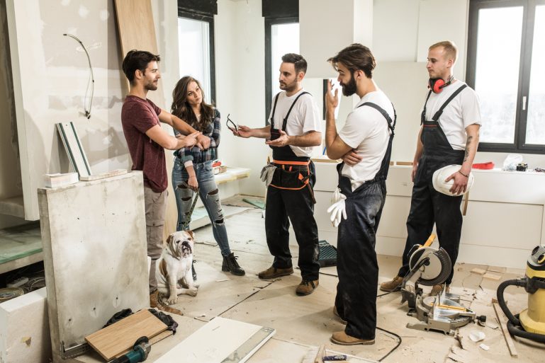 Un couple en discussion avec trois ouvriers sur un chantier de maison