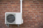 une pompe à chaleur devant un mur en brique