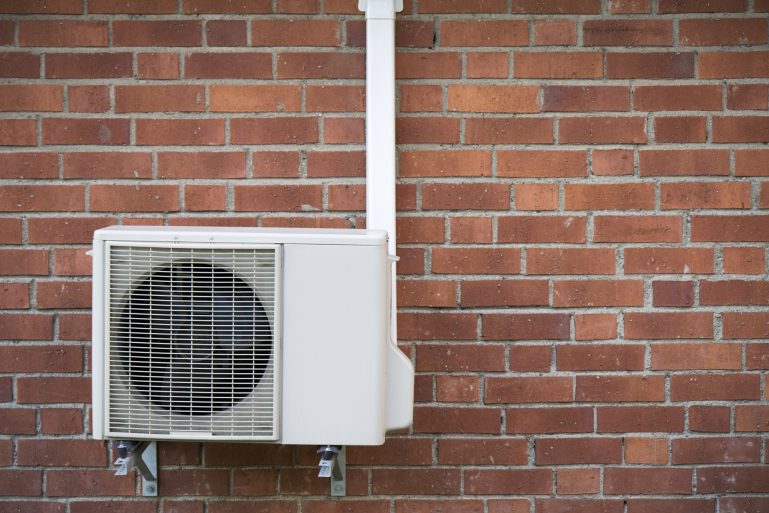 une pompe à chaleur devant un mur en brique