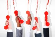 5 mains tiennent le combiné de 5 téléphones rouges