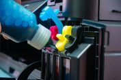 Quelqu’un remplit un réservoir d’imprimante avec un flacon d’encre bleue