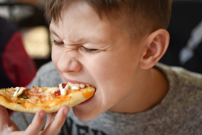 un enfant mange une pizza