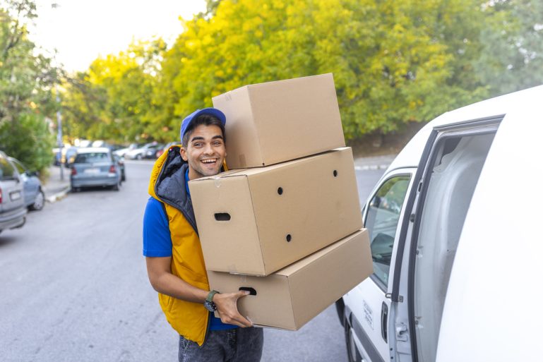 Un livreur porte trois gros cartons sur ses bras