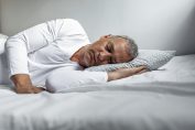 Un homme dort allongé sur un matelas, la tête sur un oreiller