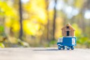 Une tiny house, en jouet miniature, en bois sur un camion miniature sur une route en forêt