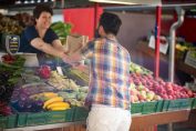 Une commerçante vend des légumes à un client sur un marché