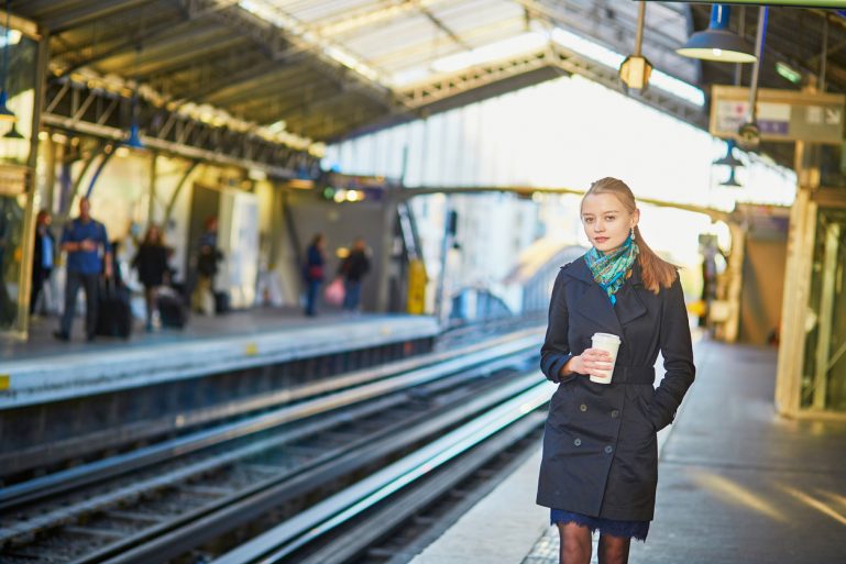 Une femme avec un mug attend sur le quai du métro