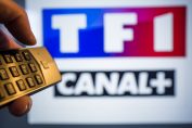 télécommande à côté d’un écran avec les logos TF1 et Canal+