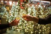 Deux personnes trinquent au crémant devant des sapins de noël