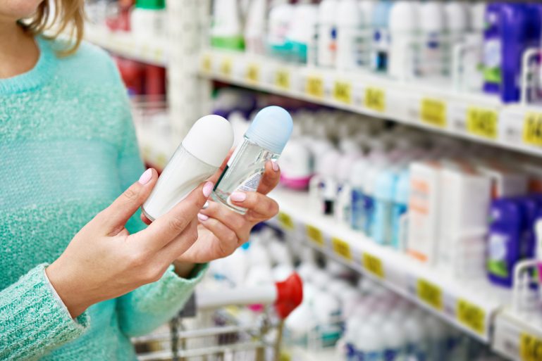 Une consommatrice compare deux déodorants en rayon